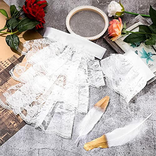 Lace fabrics, roses, feathers, and books on a textured surface.