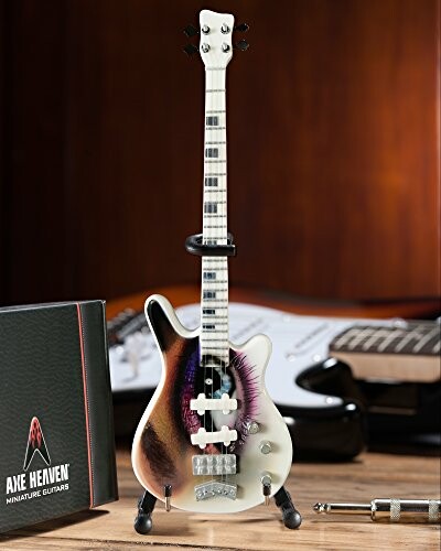 Miniature electric guitar displayed with box and background guitar.