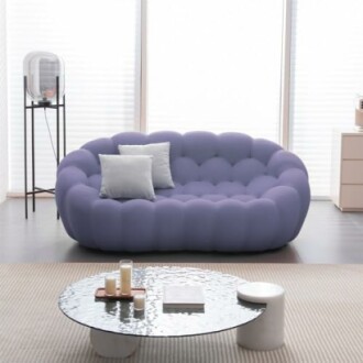 Modern living room with a purple sofa and glass coffee table.