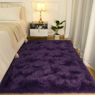 Cozy purple rug in a bedroom next to a bed and nightstand.