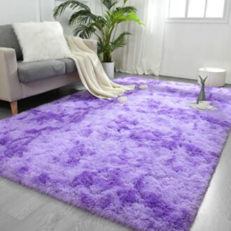 Purple fluffy rug in a living room with a grey sofa and plants.