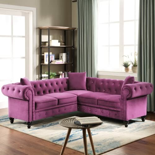 Purple velvet sectional sofa in a bright living room with a bookshelf and plants.