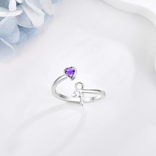 Silver ring with purple heart-shaped stone on white background.