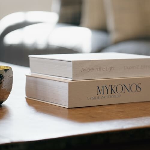 Two stacked books on a wooden table, one titled 'MYKONOS'.